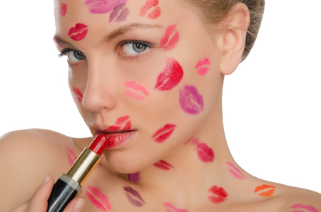 woman with kisses on face holding lipstick isolated on whiteの写真素材