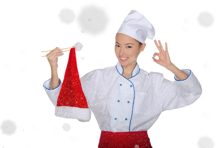 smiling asian chef in christmas cap with chopsticks under snow isolated on whiteの写真素材