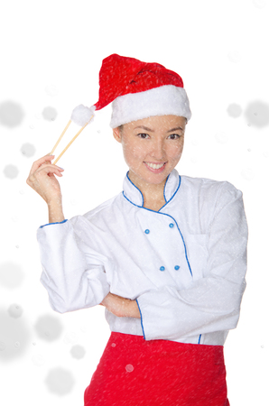 smiling asian chef in christmas outfit with chopsticks under snow isolated on whiteの写真素材