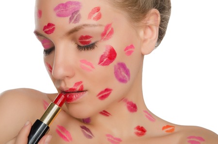Charming woman with kisses on face holding lipstick isolated on whiteの写真素材