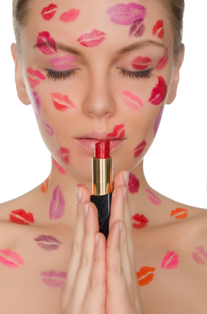 Sexy woman with kisses on face holding lipstick isolated on whiteの写真素材