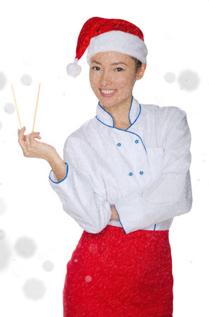 Happy asian chef in christmas outfit with chopsticks under snow isolated on whiteの写真素材