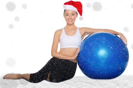 happy asian woman in christmas cap with fitball under snow isolated on whiteの写真素材