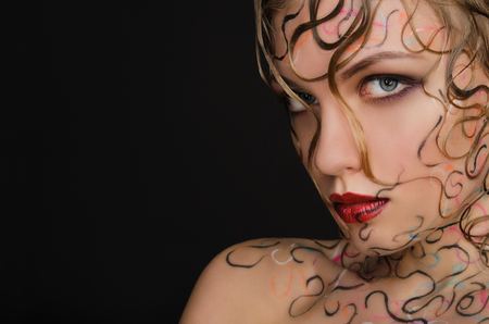 woman with wet hair and face art on black backgroundの写真素材