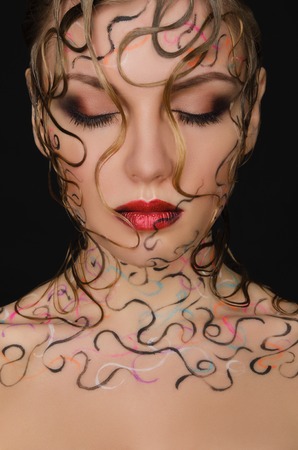 portrait of beautiful woman with wet hair and face art on black backgroundの写真素材