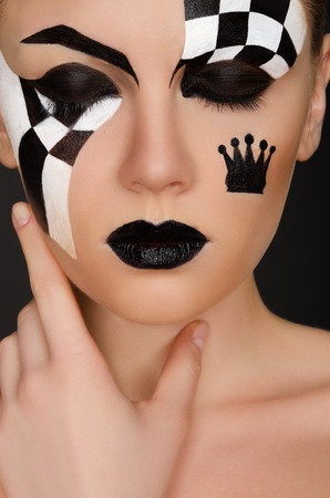portrait of young woman with black and white face art on black backgroundの写真素材