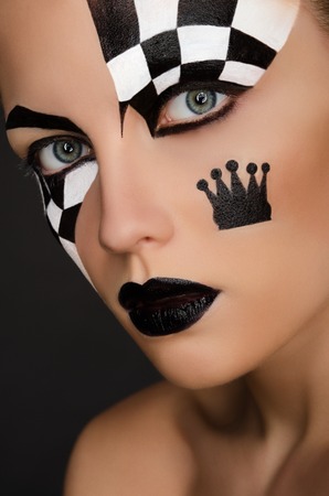 beautiful woman with black and white face art on black backgroundの写真素材
