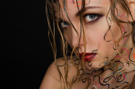 Beautiful woman with wet hair and face art on black backgroundの写真素材