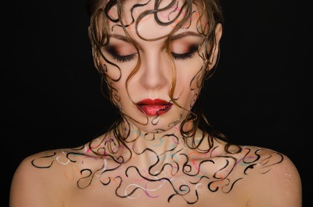 young woman with wet hair and face art on black backgroundの写真素材