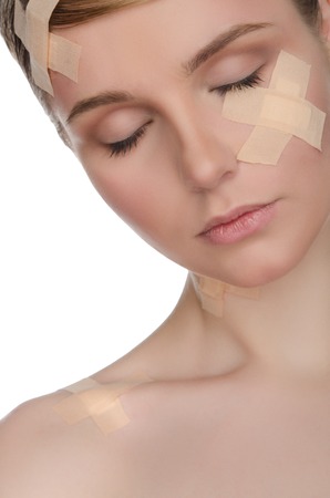 portrait of woman with medical plaster on her face isolated on whiteの写真素材