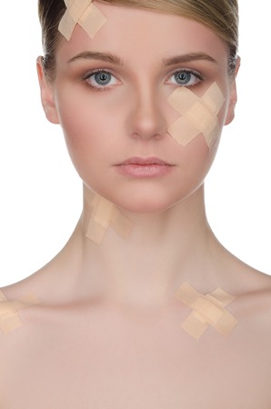 Ybeautiful woman with medical plaster on her face isolated on whiteの写真素材