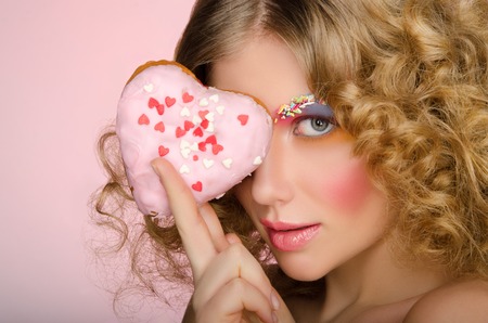 European woman with donut in face on pink backgroundの写真素材