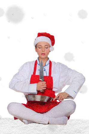 Woman cook in Santa hat, yoga, knife under snow on white backgroundの写真素材