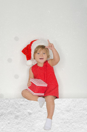 little girl in Santa suit with snowflakes with gift on gray backgroundの写真素材