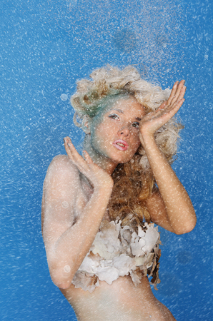 charming woman with beautiful hair and snow on blue backgroundの写真素材