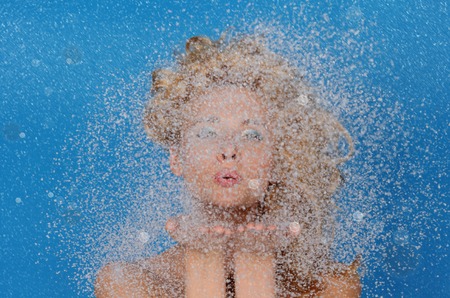 woman with beautiful hair and snow on blue backgroundの写真素材