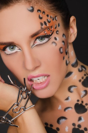 beautiful woman with animal face art and bracelet on dark backgroundの写真素材