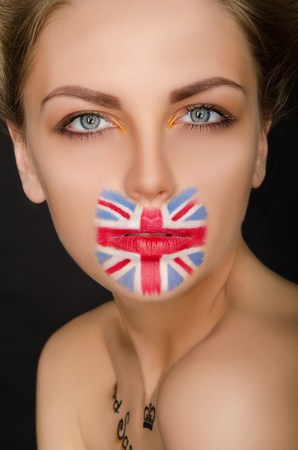 Beautiful woman with english flag on her face, black backgroundの写真素材