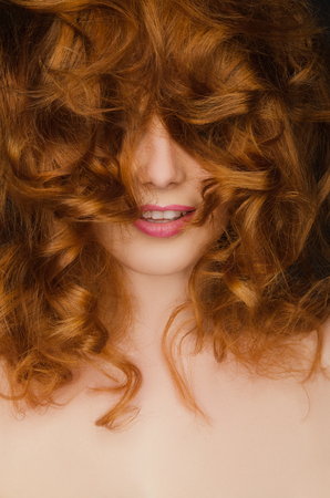 Beautiful curly red hair on the face of young womanの写真素材