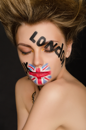 Inscriptions and flag of england on young woman's face, black backgroundの写真素材