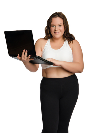 Smiling fat sporty woman with laptop isolated on whiteの写真素材