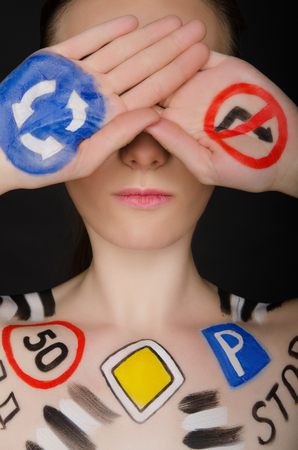 Young woman with painted road signs, dark backgroundの写真素材