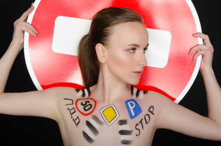 Portrait of young woman with traffic signs, a dark backgroundの写真素材