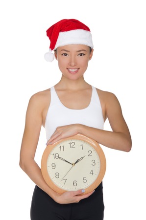 beautiful asian women in a Santa's hat with a clock isolated on whiteの写真素材