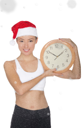 smiling asian women in a Santa's hat with a clock isolated on whiteの写真素材