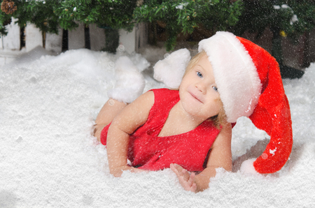 smiling girl in santa costume on white snowの写真素材