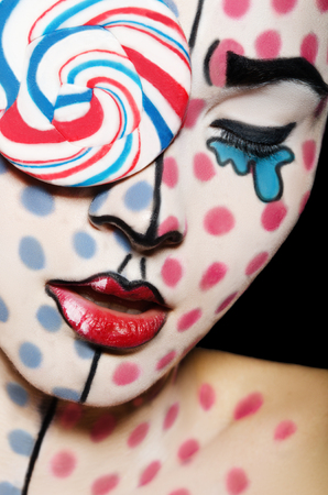 Face art with a lollipop on the face on a black backgroundの写真素材