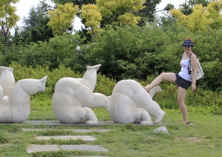 middle-aged woman in clothes for enjoying the background of the sculptural group depicting athletes in motionの写真素材
