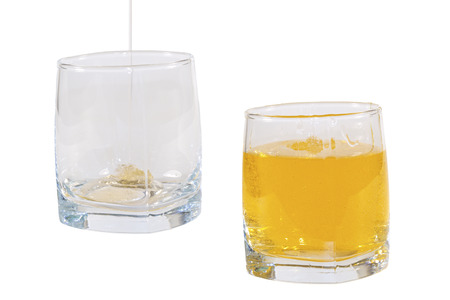rectangular glass beakers with liquids of different colors on a white background; one nearly empty, the second fullの写真素材