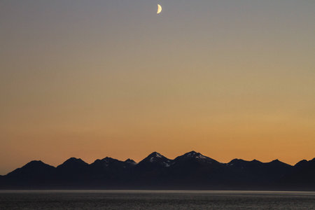 Picture of sunset over the sea with mountains and cloudsの写真素材