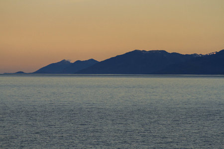Picture of sunset over the sea with mountains and cloudsの写真素材