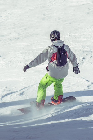 POIANA BRASOV, ROMANIA - JANUARY 24, 2016: Young snowboarder sliding on ski slope during winter season in Poiana Brasov resort, Romaniaのeditorial素材