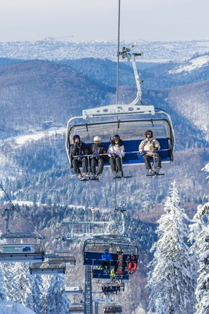 POIANA BRASOV, ROMANIA - JANUARY 24, 2016: Tourists in chairlift in winter season going to the ski slope in resort Poiana Brasov, Romaniaのeditorial素材