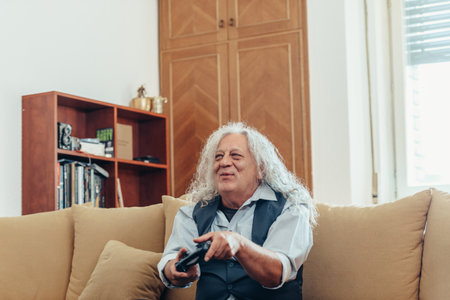 Shot of a happy senior man while holding a joystick and playing video games at homeの写真素材