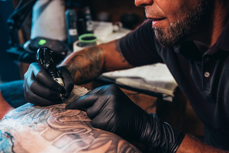 Shot of a tattoo artist at work using equipmentの写真素材