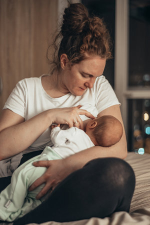 Cropped shot of an affectionate young mother breastfeeding her baby at home while sitting on a bedの写真素材