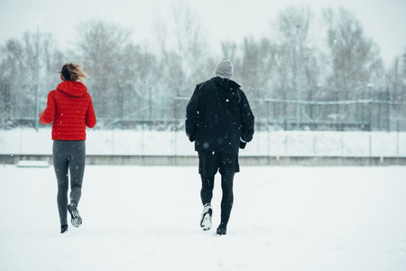 Young couple going for a run together during a snow on a cold winter dayの写真素材