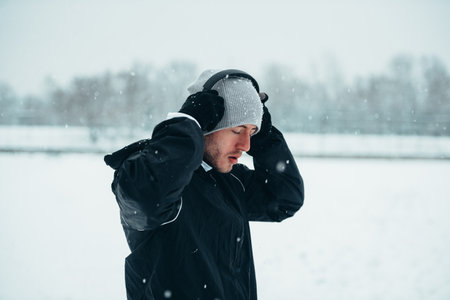 Shot of a sportsman wearing headphones while running outside on a snowy dayの写真素材