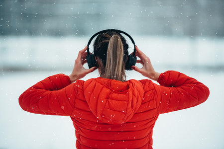 Shot of an athletic young woman running while listening some music on a cold winter dayの写真素材