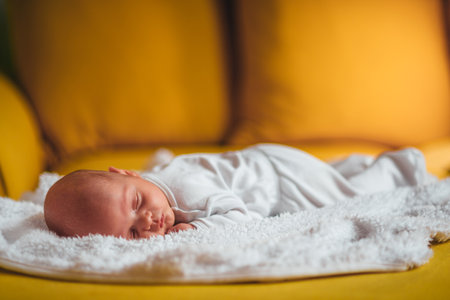 Cropped shot of an adorable baby boy sleeping on a yellow sofa at home