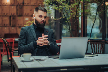 Young handsome businessman using a laptop while working in a remote office in a cafeの写真素材