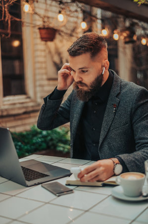 Young handsome businessman using a laptop while having an online conference in the cafeの写真素材