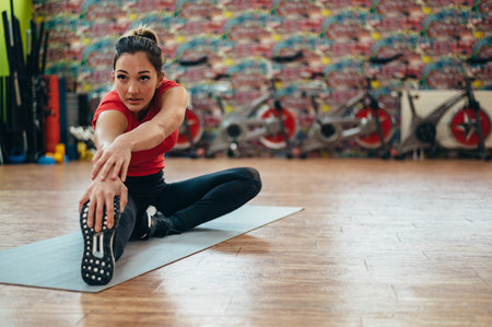 Young beautiful woman stretching in the gym while training on a fitness mat