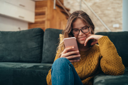 Shot of a beautiful young woman using a smartphone at homeの写真素材