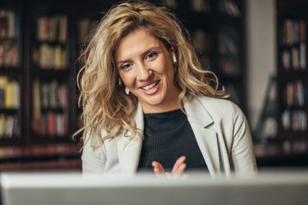 Young beautiful woman using airpods and a laptop for an online conference call with her colleagues at workの写真素材