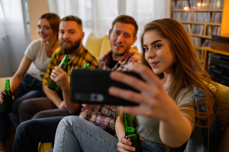 A group of friends hanging out together on a house party taking selfie with a smartphone and...
